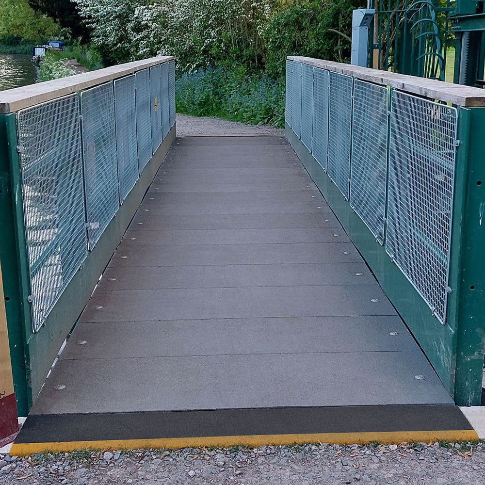 Wooden grp walkway with metal railings leading into a forested area