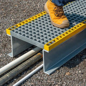 Person using a GRP Platform with yellow edges on a gravel surface