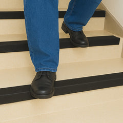 Person wearing black shoes and blue jeans ascending a set of stairs.
