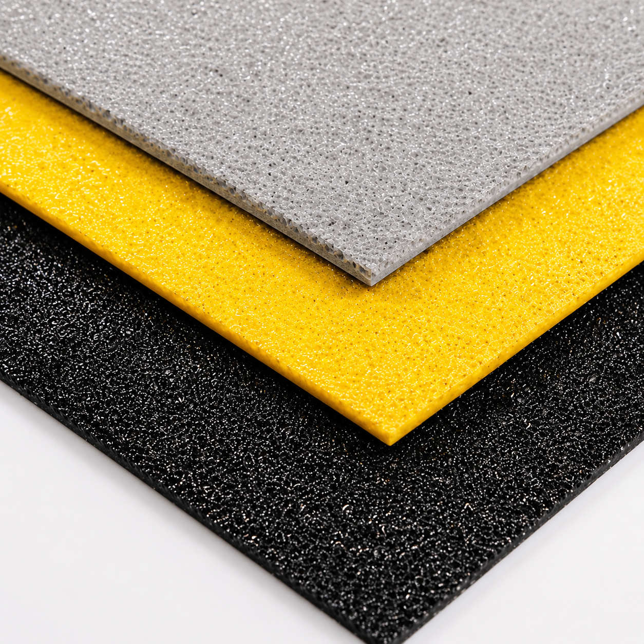 GRP Anti slip flat sheet textured rectangular mats or tiles stacked diagonally, shown in gray, bright yellow, and black on a white background