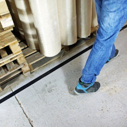 Heavy-duty black aisle marking tape applied on warehouse floor for safety and organization