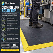 Black cushion link anti-fatigue matting in a warehouse setting, shown with a person standing on it and a yellow safety border. The left side features a black informational panel with product features and branding.