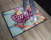 Person stepping onto a colorful doormat with 'Candy Shop' text and fruit design.