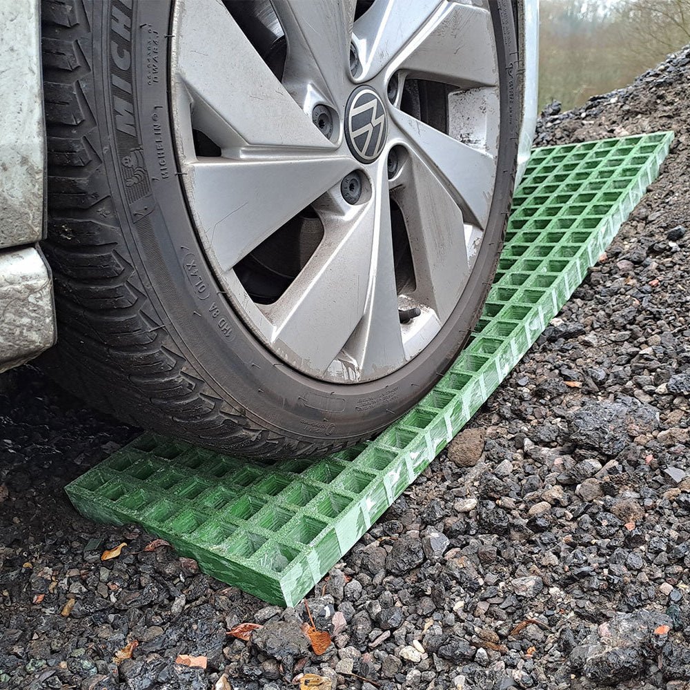 Car wheel on a green ramp on a waffle board gravel surface