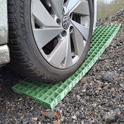Car wheel on a green ramp on a waffle board gravel surface