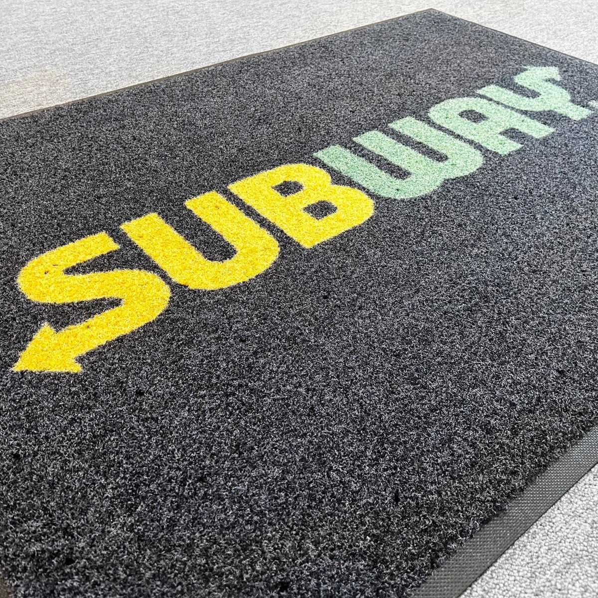 Personalised Logo Mat Indoor mat with 'Subway' logo in yellow and green on a grey surface