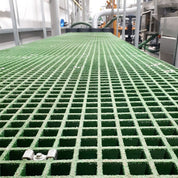 Green GRP mesh grating grid-like structure with a blurred industrial background
