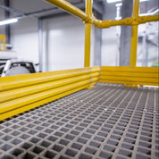 Yellow GRP mesh grating frame with a grid-like surface in an industrial setting