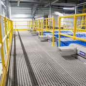 Factory floor with grey grp mesh grating panels safety railings and industrial equipment