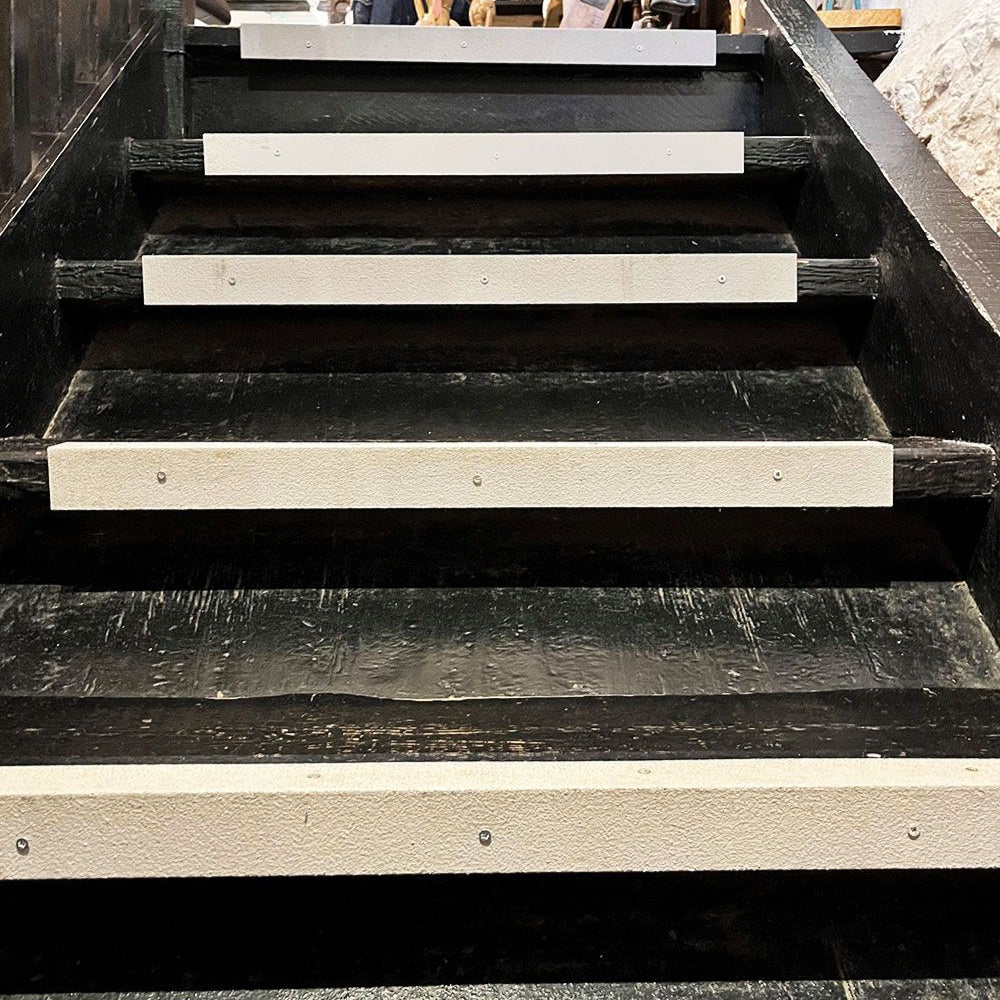 Black wooden staircase with white risers in an urban setting
