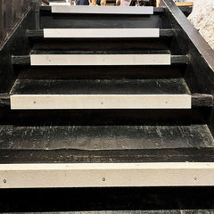 Black wooden staircase with white risers in an urban setting